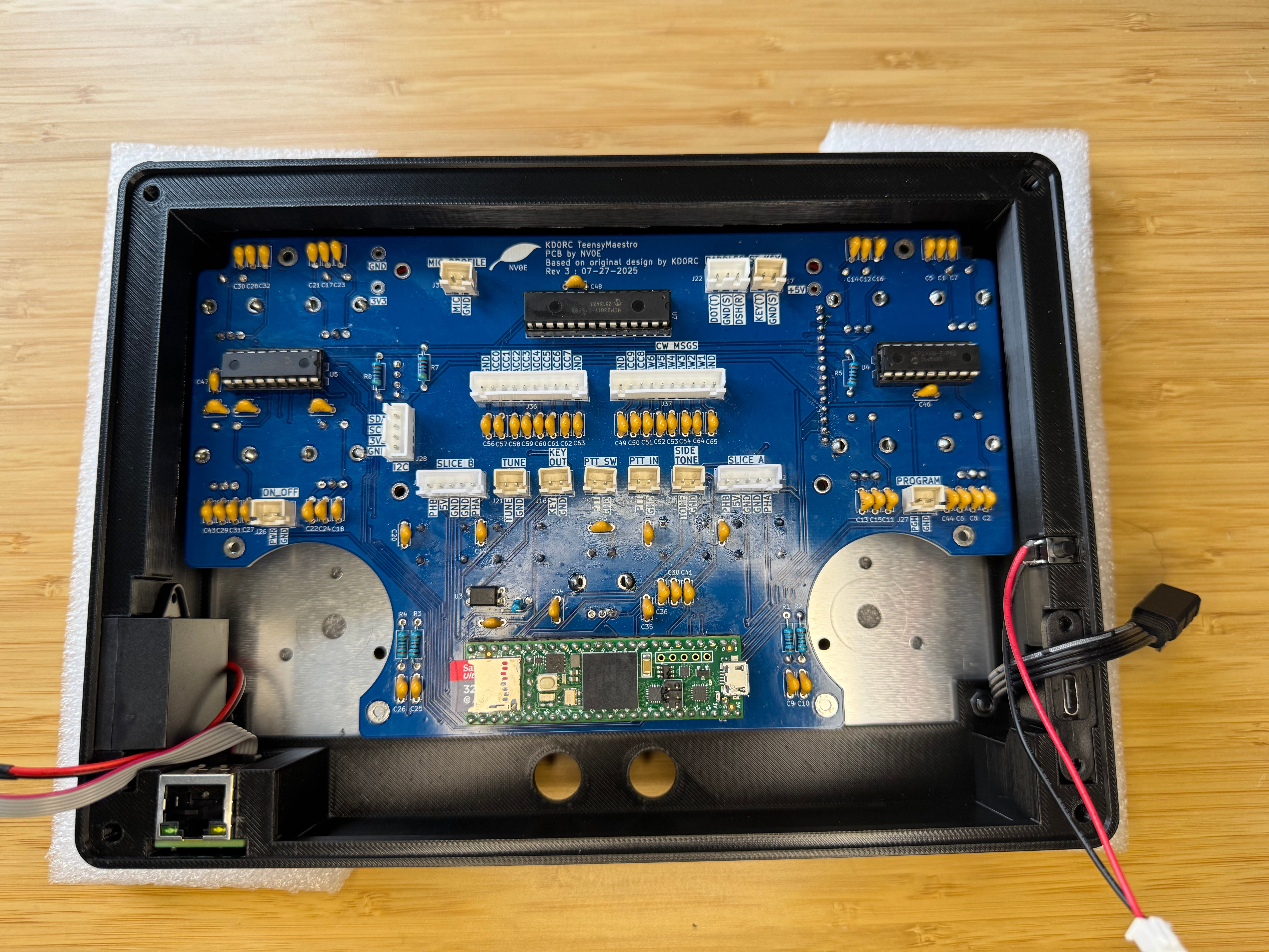 The assembled blue TeensyMaestro PCB lowered into the black case, with the Ethernet port in the bottom-left corner